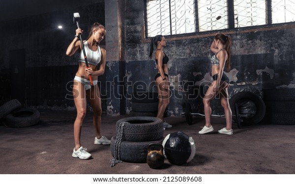 Woman working out in old garage with hammer and car\
tire .