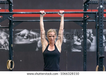 Similar – One young athletic woman at crossfit training, exercising with trx suspension fitness straps over dark background, front view, looking at camera