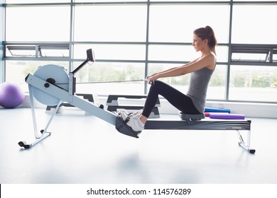 Woman working out on row machine in gym - Powered by Shutterstock