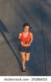 Woman Working Out In An Urban Setting, Running Along Stone Wall, Top View