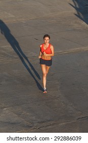 Woman Working Out In An Urban Setting, Running Along Stone Wall, Top View