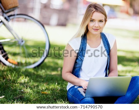 Woman working outdoors in a meadow with laptop