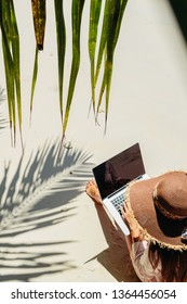 Woman Working Remotely On Laptop On Beach In Tropics. Freelancer And Blogger. Working While Travelling. Top View.