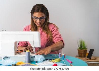 Woman working with sewing machine doing homemade medical face mask for preventing and stop corona virus spreading - Textile seamstress and healthcare people concept  - Powered by Shutterstock