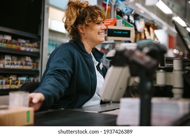 Woman Working At Supermarket Checkout Serving Customers. Friendly Cashier Working At Grocery Store Checkout.