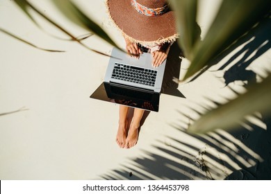 woman working through internet in tropics. Working remotely on the laptop computer through the internet. Working while travelling. top view.