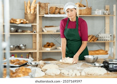 Woman works in bakery as baker, kneads dough, works with flour. Working moment, process of creating croissants in bakery - Powered by Shutterstock