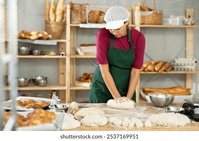 Woman works in bakery as baker, kneads dough, works with flour. Working moment, process of creating croissants in bakery - Powered by Shutterstock