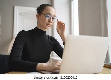 The woman works with glasses, uses a laptop, writes a reply message to the client by mail. Company Report
