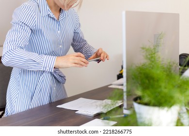 A woman works in the office, holds a phone in her hands and photographs documents.Business woman works at a computer at home or in the office.Work, office, online, freelance, remote work, business