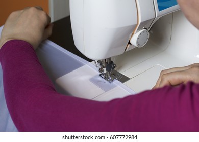 A Woman Works On A Sewing Machine. She Sews The Curtains On The Window.