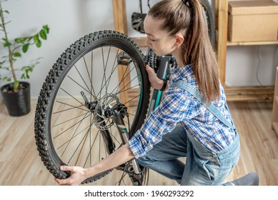A woman in the workshop is disassembling his bike and repairing it. Concept of maintenance and preparation for the new season - Shutterstock ID 1960293292