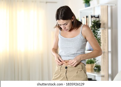 Woman Worried About Body Fat Touching Her Belly Standing At Home