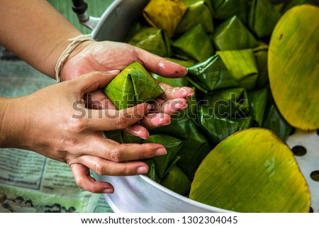 A woman wrapped Stuffed Dough Pyramid with banana leaf, It's a Thai dessert used for Chinese festival.