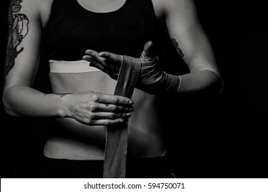 Woman wrapping hands with boxing wraps in dark room. Close-up black and white shot - Powered by Shutterstock