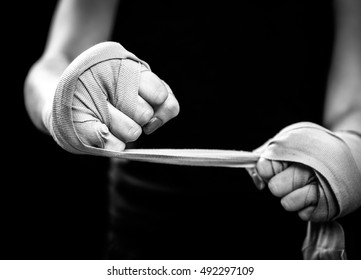 Woman is wrapping hands with pink boxing wraps. Isolated on black with red nails. Strong hand and fist, ready for fight and active exercise - Powered by Shutterstock