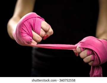 Woman is wrapping hands with pink purple boxing wraps. Isolated on black with red nails. Strong hand and fist, ready for fight and active exercise. Women self defense. - Powered by Shutterstock