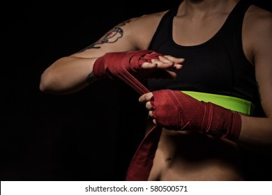 Woman wrapping hands with red boxing wraps in dark room. Close-up shot - Powered by Shutterstock