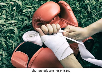 Woman is wrapping hands with white boxing wraps, Strong hand and fist, ready for fight and active exercise, Boxing gloves, Women self defense. (Vintage Film Style Process) - Powered by Shutterstock