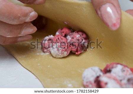 A woman wraps starchy cherries in a dough on the rolled dough. Cooking dumplings. Close-up shot.