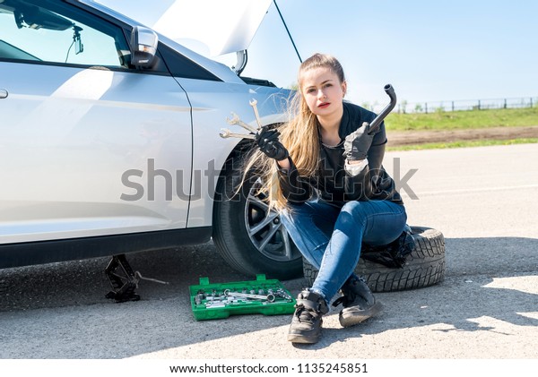 Woman with wrenches\
have a problem with car