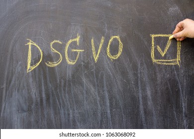 A woman writes the letters "DSGVO" on a blackboard with chalk. Black chalkboard with the inscription DSGVO (Datenschutzgrundverordnung) in English GDPR (General Data Protection Regulation).
