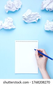 Woman writes in notebook around crumpled paper in the form of clouds on blue background. Concept of drawing up wish list and dreams, head in the clouds