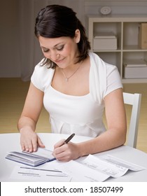 Woman Writing Checks From Checkbook To Pay Monthly Bills