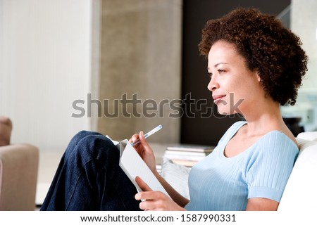 Woman writing a diary or journal, relaxing at home