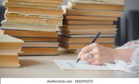 Woman Writing Essay Or Love Letters On A Piece Of White Paper In Library. Closeup Of Female Hands With Ring,  Writing Notes. Handwritten Text