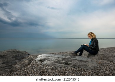 Woman writing her thoughts or poetry by the sea