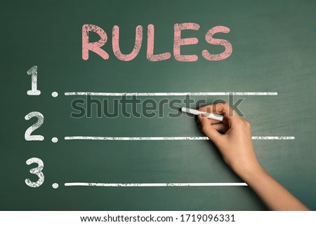 Woman writing list of rules on chalkboard, closeup 