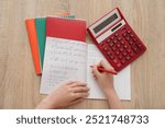 Woman writing math formulas in copybook on wooden table