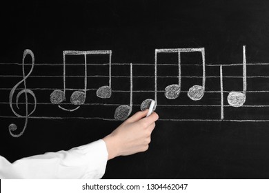 Woman Writing Music Notes With Chalk On Blackboard, Closeup