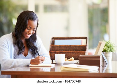 Woman Writing In Notebook Sitting At Desk