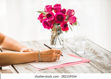 Woman writing on  blank paper sheets on old wooden table
