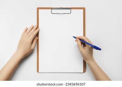 woman writing on a blank white sheet of paper pinned to a clipboard on a white table