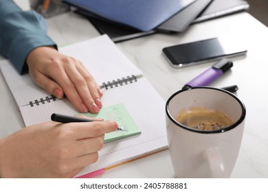 Woman writing on sticky note at white marble table, closeup - Powered by Shutterstock