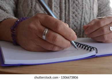 Woman Writing In A Spiral Bound Notebook, Pen In Hand