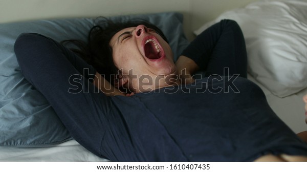 \
Woman yawning in bed morning. Real life authentic\
person yawn