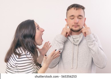 Woman Yelling At Her Boyfriend In Hysterics. Young Man Covers His Ears, Not Wanting To Listen To It