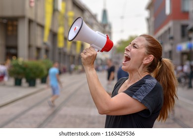 Woman Yelling Into A Bullhorn On An Urban Street Voicing Her Displaeasure During A Protest Or Demonstration Close Up Side View Of Her Face