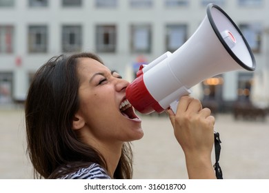 Woman Yelling Into A Bullhorn On An Urban Street Voicing Her Displaeasure During A Protest Or Demonstration, Close Up Side View Of Her Face