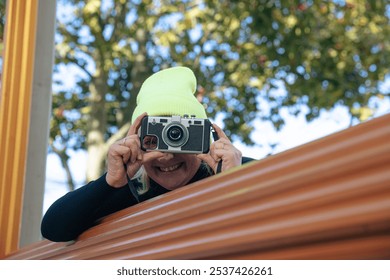 Woman in yellow beanie using vintage camera outdoors in autumn - Powered by Shutterstock