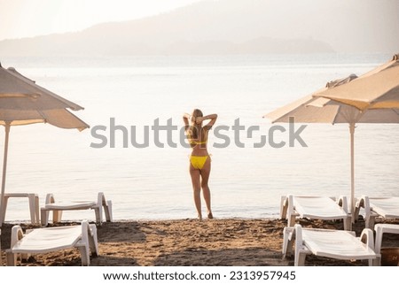 a woman in a yellow bikini on the beach