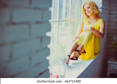 Woman In A Yellow Dress Sitting By The Window