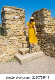 Woman in yellow dress and straw hat walks in Akkerman fortress, medieval castle near the sea. Stronghold in Ukraine. Ruins of the citadel of the Bilhorod-Dnistrovskyi fortress, Ukraine. Summer travel.