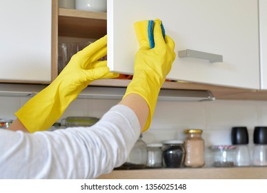 Woman In Yellow Gloves Washes The Door In Kitchen Cabinet