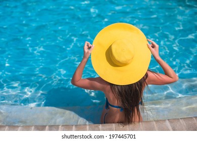 Woman In Yellow Hat Relaxing At Swimming Pool