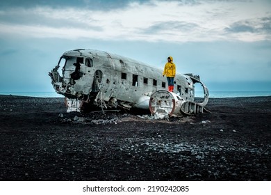Woman in yellow jacket on Solheimasandur Plane Wreck in Iceland. Traveling in Iceland